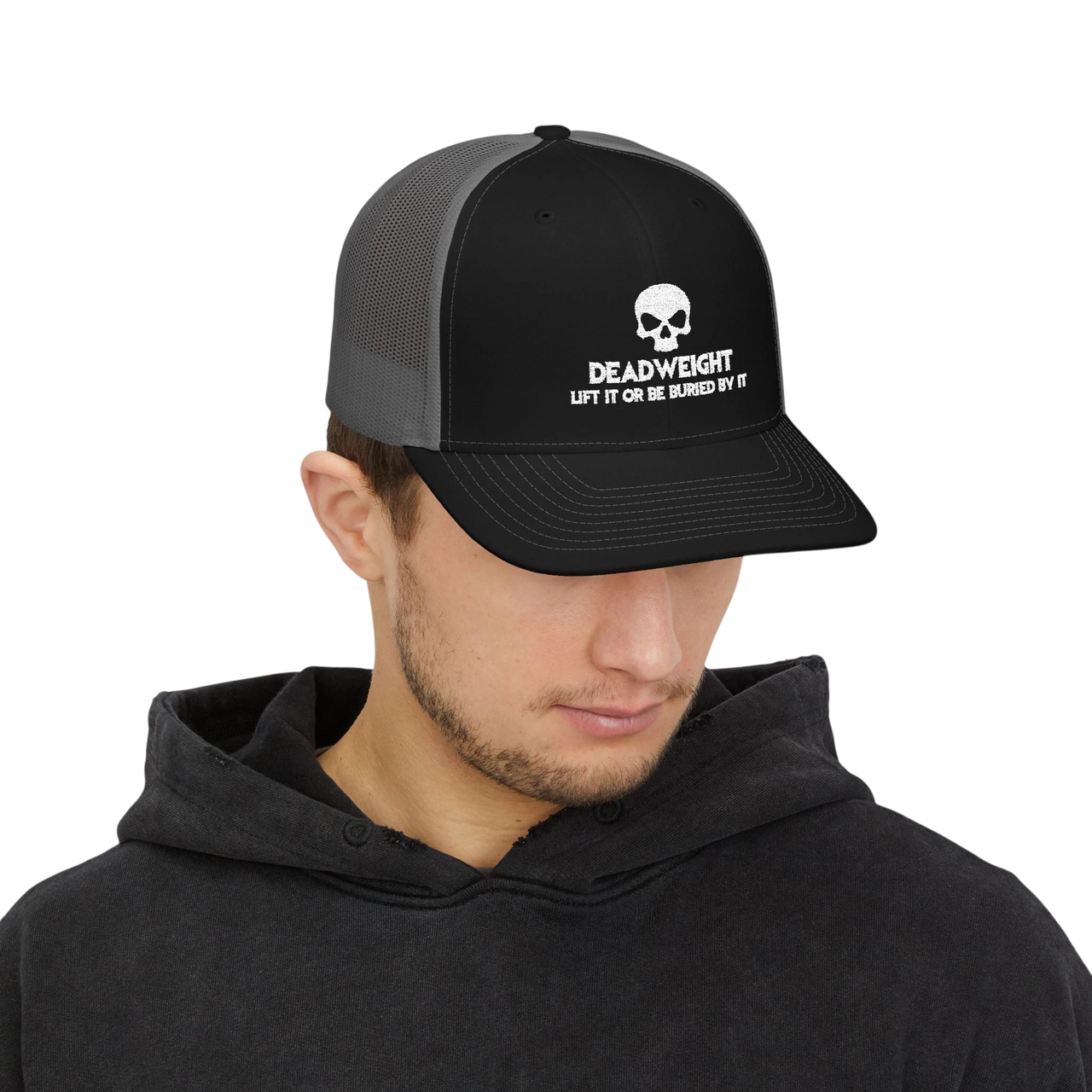DailyThreadCo. black and grey trucker cap with skull logo worn by a man in a black hoodie.