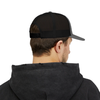 DailyThreadCo. black and grey trucker cap with mesh back worn by a man in a dark hoodie, rear view