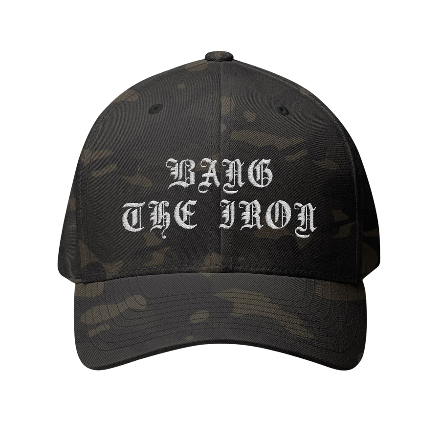 DailyThreadCo. structured FlexFit cap in dark camo with white Bang the Iron gothic embroidery on the front.