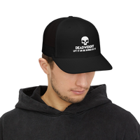 DailyThreadCo. black trucker cap with white skull Deadweight logo worn by a man in a black hoodie.