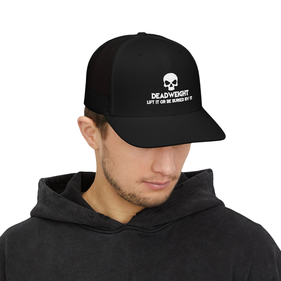 DailyThreadCo. black trucker cap with white skull Deadweight logo worn by a man in a black hoodie.