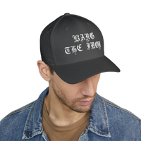 DailyThreadCo. structured FlexFit cap in dark grey with white gothic Bang the Iron embroidery on a man in denim