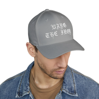 DailyThreadCo. grey structured FlexFit cap with white gothic Bang the Iron embroidery worn by a man in a denim jacket.