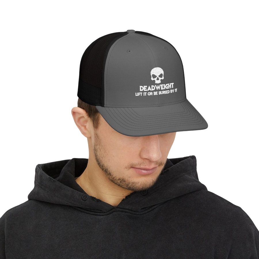DailyThreadCo. grey and black trucker cap with a white skull Deadweight logo worn by a man in a black hoodie.